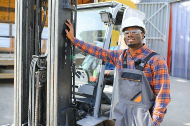 mutlu bir Afro-Amerikan erkek işçinin işyerinde forklift sürüş portresi.