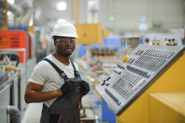 Endüstriyel mühendis portresi. Fabrika üretim hattında duran kasklı gülen fabrika işçisi..