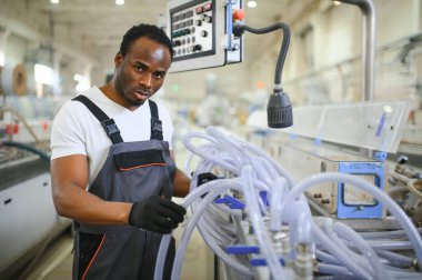 Üniformalı ve endüstriyel fabrikada ayakta duran Afrikalı Amerikalı erkek mühendisin portresi.