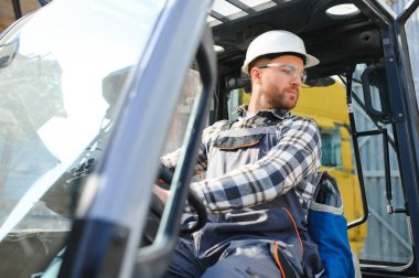 Forklift kullanan bir adam büyük bir depoda çalışır ve bir çanta dolusu hammaddeyi boşaltır..