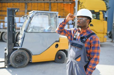 mutlu bir Afro-Amerikan erkek işçinin işyerinde forklift sürüş portresi.