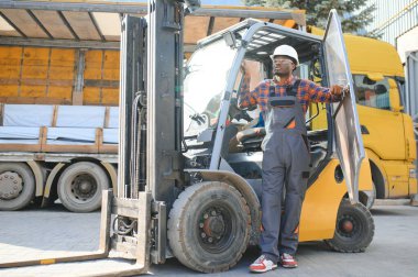 mutlu bir Afro-Amerikan erkek işçinin işyerinde forklift sürüş portresi.