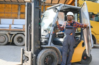 mutlu bir Afro-Amerikan erkek işçinin işyerinde forklift sürüş portresi.