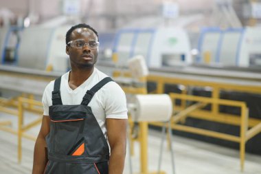 Endüstriyel mühendis portresi. Fabrika üretim hattında duran kasklı gülen fabrika işçisi..