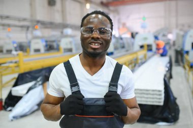 Üniformalı ve endüstriyel fabrikada ayakta duran Afrikalı Amerikalı erkek mühendisin portresi.