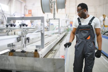 Plastik pencere çerçevesi fabrikasında çalışan Afro-Amerikalı bir erkek işçi..