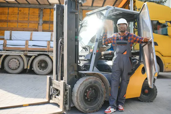 African logistics man as a forklift driver in the warehouse of a freight forwarder.