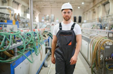 Gülümseyen ve mutlu çalışan. Fabrikada sanayi işçisi. Sert şapkalı genç teknisyen.
