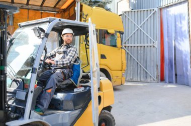 Fabrika deposundaki profesyonel forklift sürücüsünün portresi..