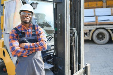 mutlu bir Afro-Amerikan erkek işçinin işyerinde forklift sürüş portresi.