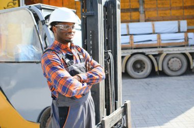 mutlu bir Afro-Amerikan erkek işçinin işyerinde forklift sürüş portresi.