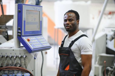Endüstriyel mühendis portresi. Gülümseyen fabrika işçisi fabrika üretim hattında duruyor..