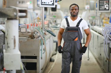 Endüstriyel mühendis portresi. Gülümseyen fabrika işçisi fabrika üretim hattında duruyor..