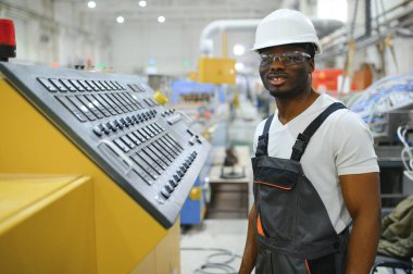 Endüstriyel mühendis portresi. Fabrika üretim hattında duran kasklı gülen fabrika işçisi..