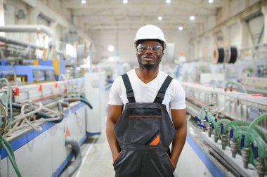 Endüstriyel mühendis portresi. Fabrika üretim hattında duran kasklı gülen fabrika işçisi..