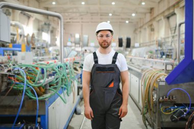 Özel üniformalı ve beyaz kasklı bir erkek işçi. PVC pencereleri için çerçeve üretimi.