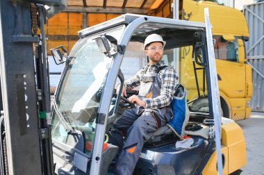 Ağır endüstri forklift sürücüsünün portresi baş parmak kaldırıyor ve gülümsüyor..