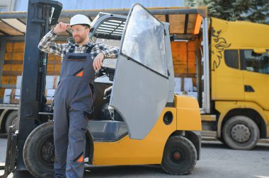 Ağır endüstri forklift sürücüsünün portresi baş parmak kaldırıyor ve gülümsüyor..