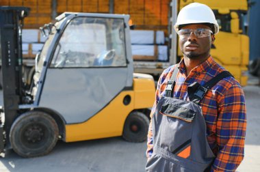 mutlu bir Afro-Amerikan erkek işçinin işyerinde forklift sürüş portresi.