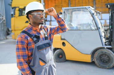 Afro-Amerikan Adam iş başında. Profesyonel operasyon mühendisliği. Genç işçi forklift sürücüsü.