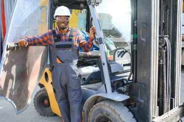 mutlu bir Afro-Amerikan erkek işçinin işyerinde forklift sürüş portresi.