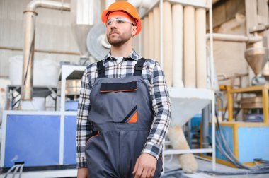 Gülümseyen ve mutlu çalışan. Fabrikada sanayi işçisi. Sert şapkalı genç teknisyen.