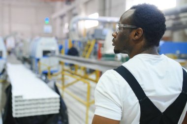 Üniformalı ve endüstriyel fabrikada ayakta duran Afrikalı Amerikalı erkek mühendisin portresi.