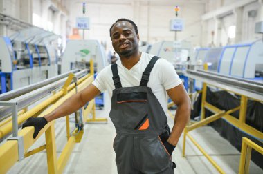 Üniformalı ve endüstriyel fabrikada ayakta duran Afrikalı Amerikalı erkek mühendisin portresi.