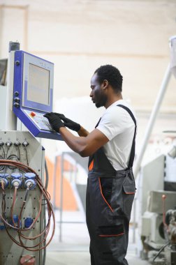 Endüstriyel mühendis portresi. Gülümseyen fabrika işçisi fabrika üretim hattında duruyor..