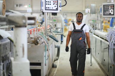 Plastik pencere çerçevesi fabrikasında çalışan Afro-Amerikalı bir erkek işçi..