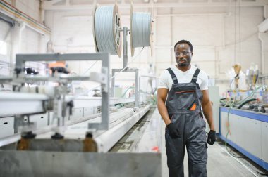Endüstriyel mühendis portresi. Gülümseyen fabrika işçisi fabrika üretim hattında duruyor..
