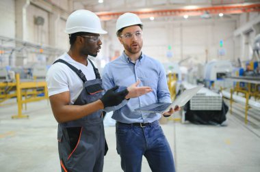 Bir mühendis üretim hattındaki bir işçiyle iletişim kurar..