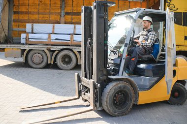 Fabrika deposundaki profesyonel forklift sürücüsünün portresi..
