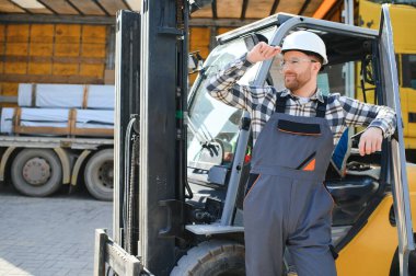 Ağır endüstri forklift sürücüsünün portresi baş parmak kaldırıyor ve gülümsüyor..