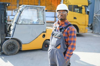 mutlu bir Afro-Amerikan erkek işçinin işyerinde forklift sürüş portresi.
