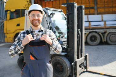 Ağır endüstri forklift sürücüsünün portresi baş parmak kaldırıyor ve gülümsüyor..