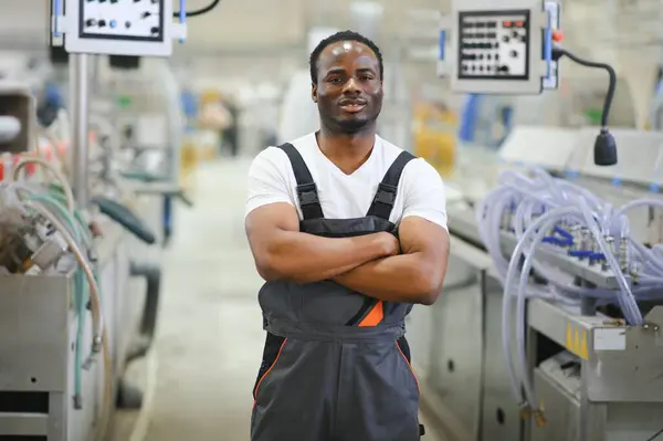 Portrait of industrial engineer. Smiling factory worker standing in factory production line.