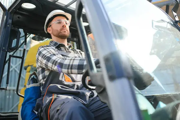 Portrait of heavy industry forklift driver giving thumbs up and smiling.