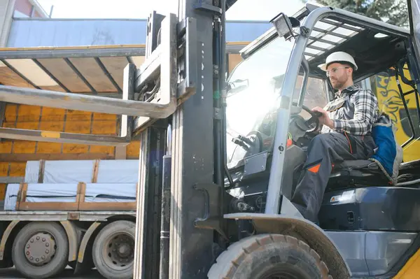 Portrait of heavy industry forklift driver giving thumbs up and smiling.