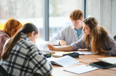 Test. Üst üste oturan ve test kitaplarında sınava sahip genç öğrencilerin yakın çekim.