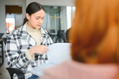 Öğrenciler sınıfta oturuyor, çalışıyor, tartışıyorlar..