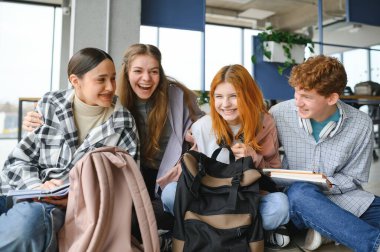 Bir grup neşeli öğrenci bir sınıfta yerde oturuyorlar..