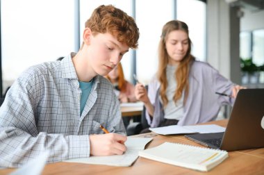 Öğrenciler sınıfta oturuyor, çalışıyor, tartışıyorlar..