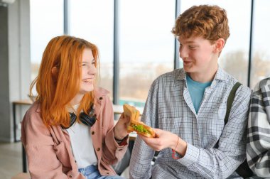 Bir grup genç öğrenci öğle yemeği molası verip sandviç yiyorlar..