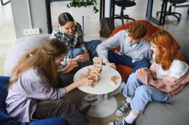 Bir grup yaratıcı arkadaş ahşap masada oturuyor. İnsanlar masa oyunu oynarken eğleniyor.