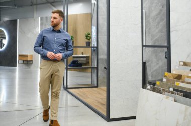 Orta yaşlı bir adam ev banyosu için seramik fayans ve kap kacak seçiyor..