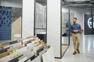 Orta yaşlı bir adam ev banyosu için seramik fayans ve kap kacak seçiyor..