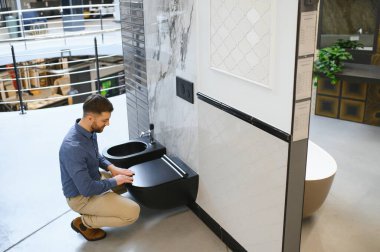 Adam inşaat süpermarketinde seramik klozet seçiyor..