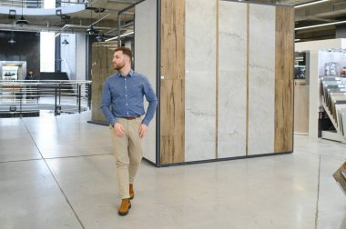 Orta yaşlı bir adam ev banyosu için seramik fayans ve kap kacak seçiyor..