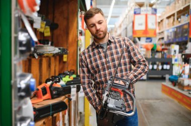 Alet deposunda elektrikli testereyi tutan çalışma.